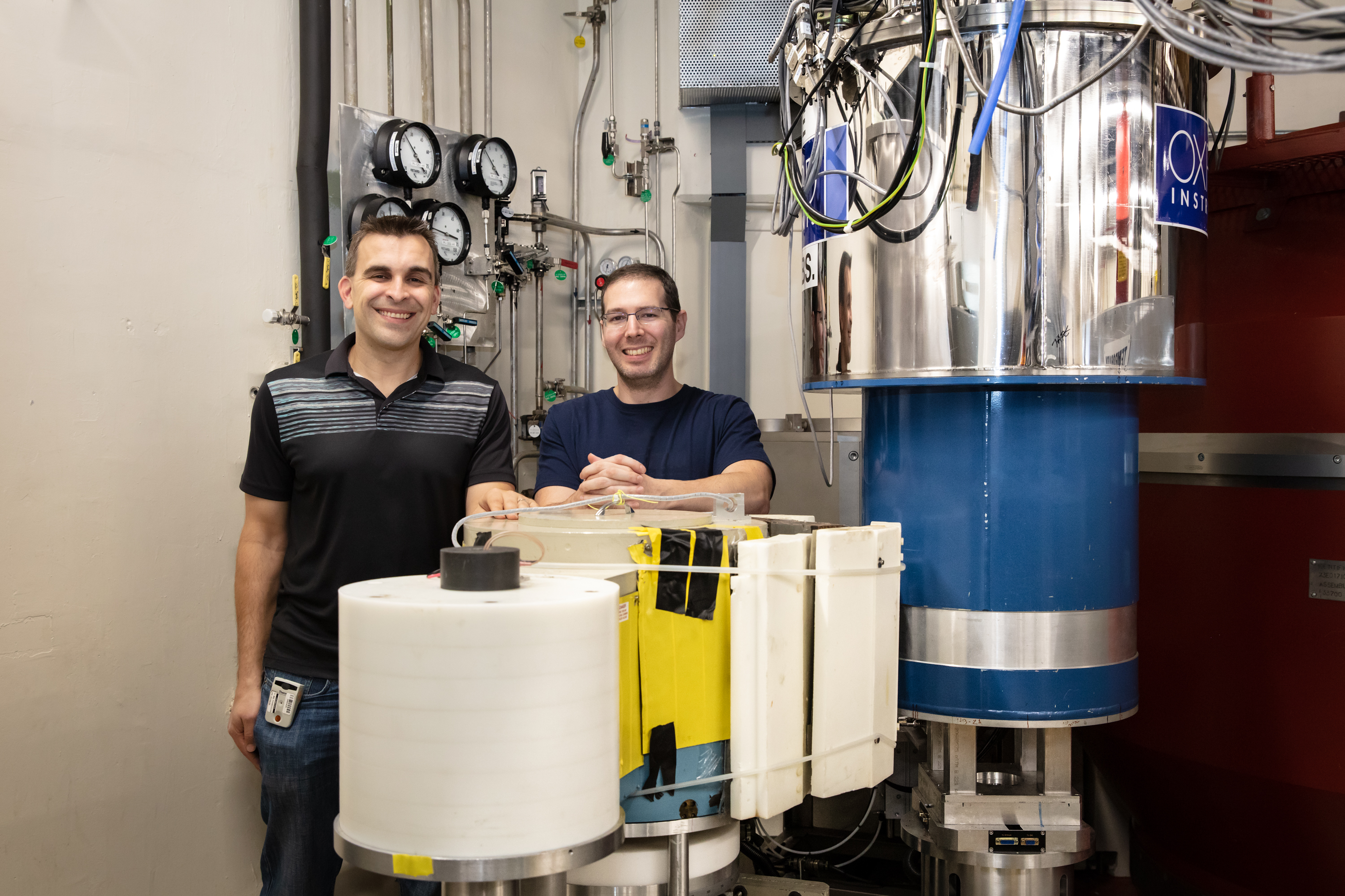 ORNL scientists Adam Aczel and Gabriele Sala stand beside the High Flux Isotope Reactor’s FIE-TAX instrument. Ross and her team used FIE-TAX to explore ytterbium silicate’s microstructure and find evidence for a BEC phase. (Credit: ORNL/Genevieve Martin)