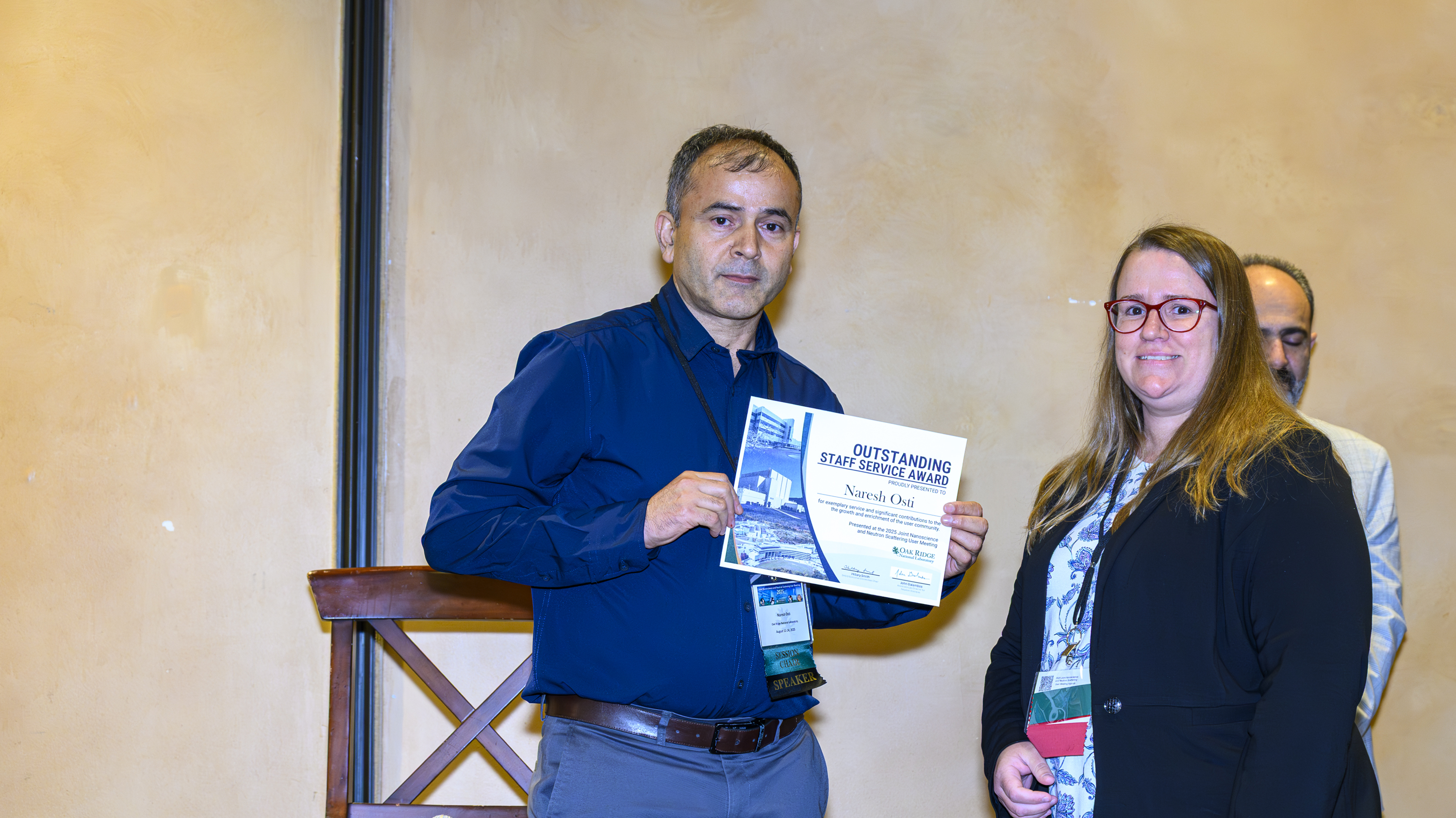 A man and woman smiling as Award winner Naresh Osti holds certificate for Outstanding Staff Service Award