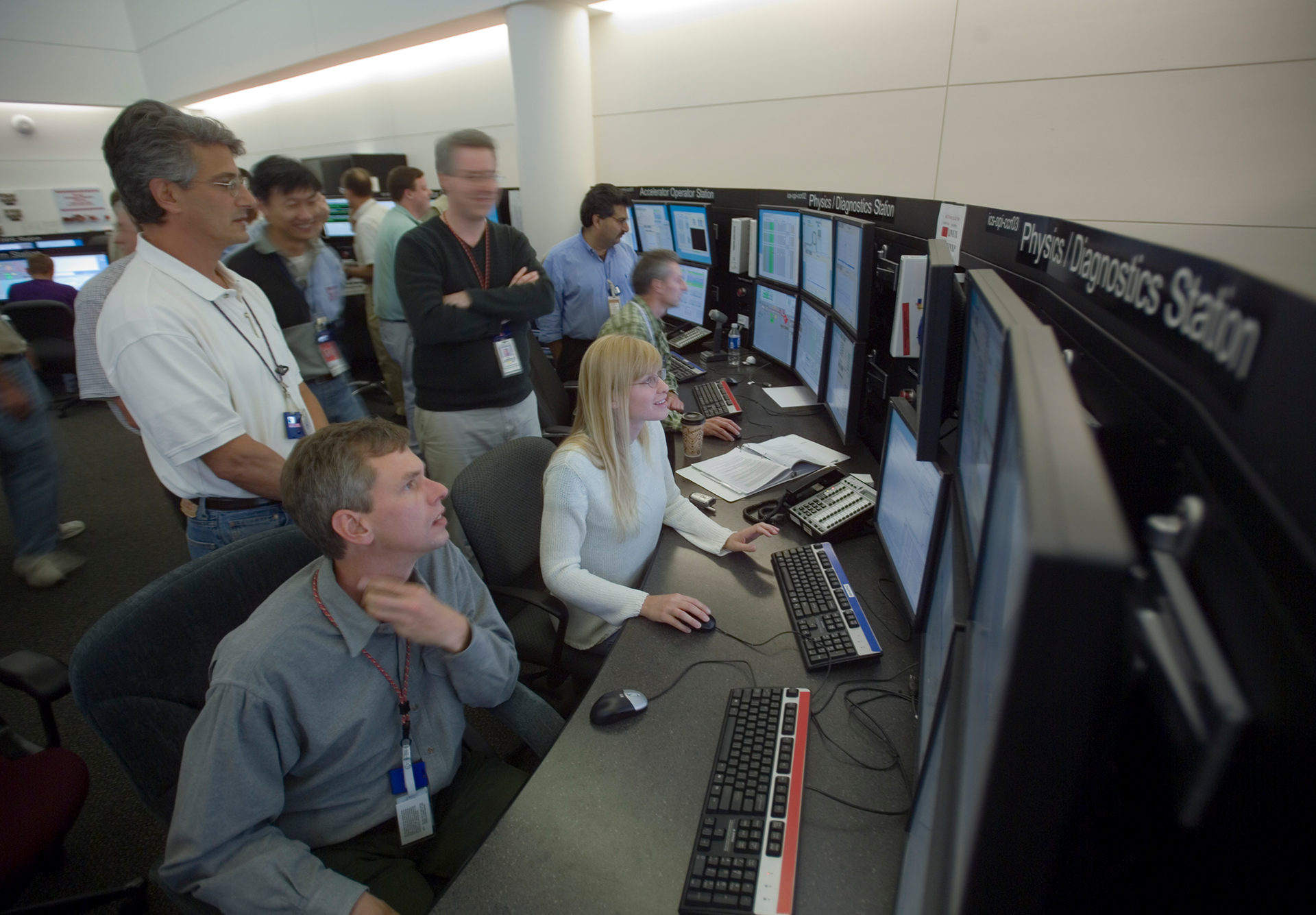 John Galambos (standing, left) watches as the Spallation Neutron Source becomes operational on April 28, 2006