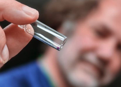 Scientist holding a small vial with a glass bead