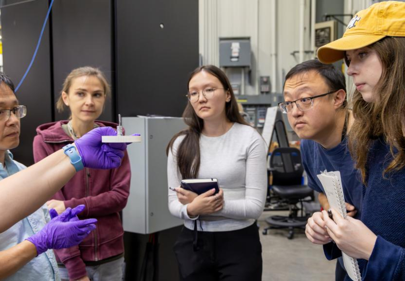 Lisa Debeer-Schmitt, a neutron scattering scientist at ORNL, holds a sample mount while explaining sample preparation and positioning to students, including Michelle Sandag, at the General Purpose Small-Angle Neutron Scattering Diffractometer. Credit: Alo