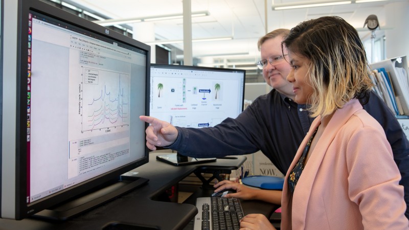 ORNL researchers Garrett Granroth and Fahima Islam observe data filtered through their new software, which gives researchers access to data with five times more resolution than traditional data reduction methods. (Credit: ORNL/Genevieve Martin)