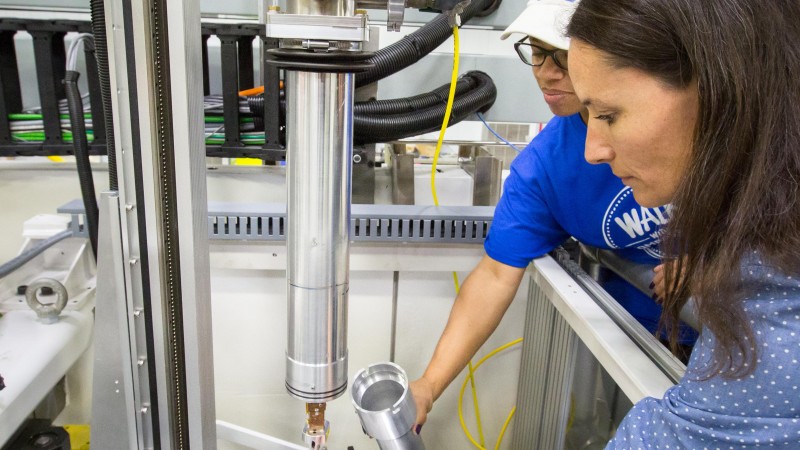 Instrument scientist Flora Meilleur (right) and scientific associate Lakeisha Walker (left) prepare to load a sample onto the CCR cold finger. Temperature is controlled by a LakeShore model 340 cryogenic temperature controller (not shown; LakeShore Cryotronics, Inc.). The inner heat shield (not shown) and outer vacuum can are made of amorphous aluminum to minimize background. Image credit: Genevieve Martin/ORNL