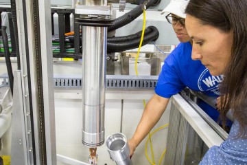 Instrument scientist Flora Meilleur (right) and scientific associate Lakeisha Walker (left) prepare to load a sample onto the CCR cold finger. Temperature is controlled by a LakeShore model 340 cryogenic temperature controller (not shown; LakeShore Cryotronics, Inc.). The inner heat shield (not shown) and outer vacuum can are made of amorphous aluminum to minimize background. Image credit: Genevieve Martin/ORNL